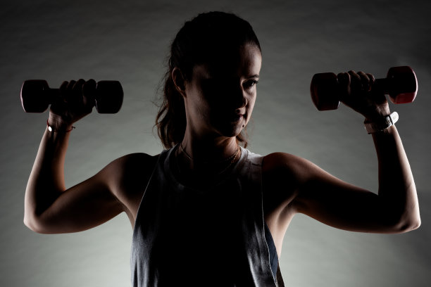 健身女孩摆姿势和举重。积极的笑容。图片下载
