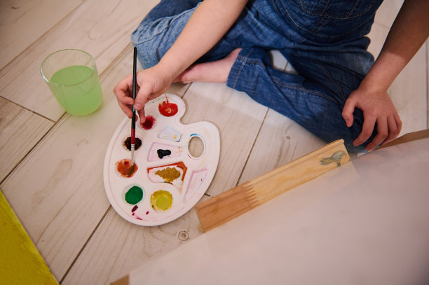 俯视图的一个小艺术家持有画笔和混合水彩颜料在调色板上画在画布上的艺术绘画课。孩子们娱乐的概念图片下载