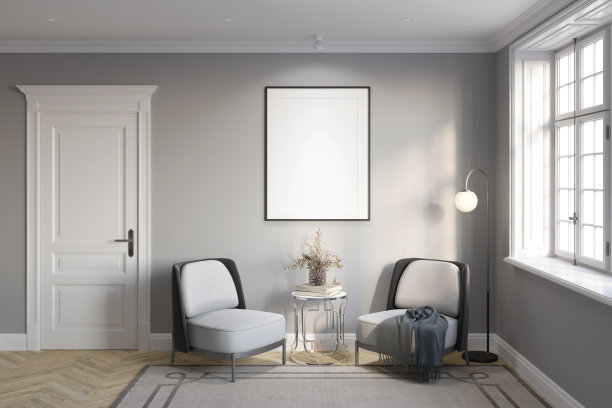在一扇古色古香的门和一扇窗之间，灰色的墙上贴着一张垂直的空白海报，在扶手椅和一盏灯旁边的咖啡桌上放着一瓶花，拼花地板上铺着地毯。图片下载