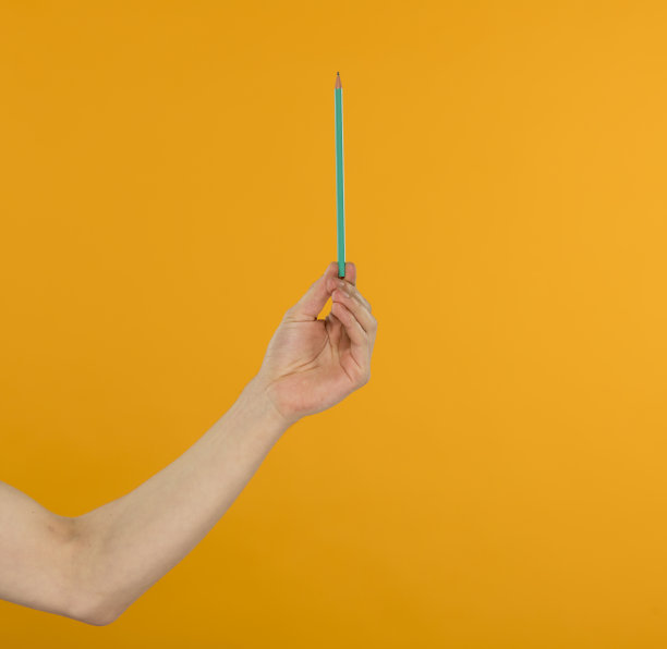 一个男人的手握着一支绿色的铅笔在亮黄色的特写镜头上图片下载