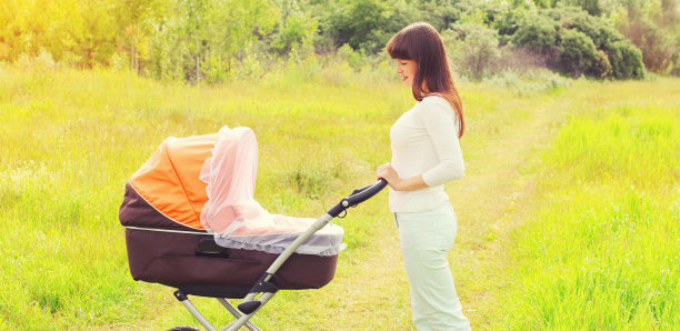 快乐微笑的母亲走在户外的自然婴儿车婴儿图片下载