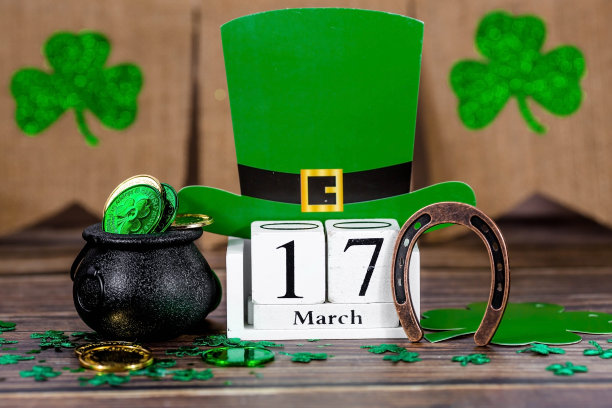 3月17日圣帕特里克节的白色复古日历，木制背景上有一个幸运的马蹄铁和一罐金子。图片下载