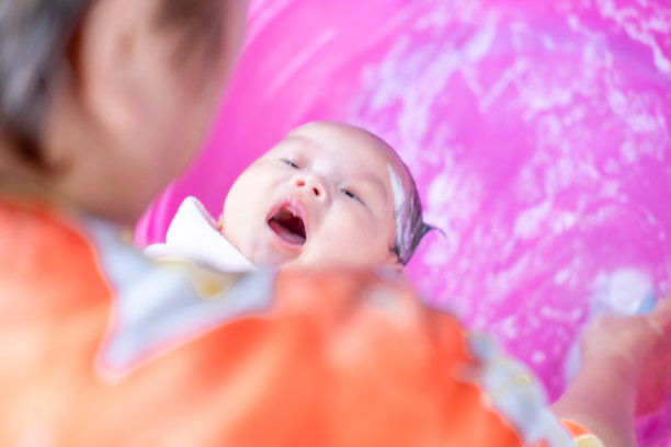 亚洲妈妈沐浴宝宝清洁污垢给宝宝洗澡容器清洁生活方式家庭之间的母亲和孩子之间用于婴儿沐浴露产品，洗发水和婴儿护理产品图片下载