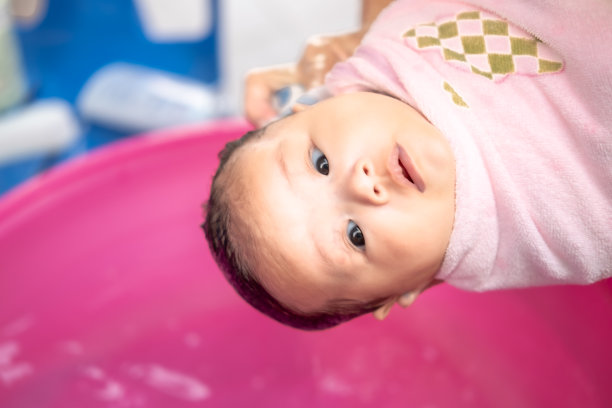 亚洲妈妈沐浴宝宝清洁污垢给宝宝洗澡容器清洁生活方式家庭之间的母亲和孩子之间用于婴儿沐浴露产品，洗发水和婴儿护理产品图片下载