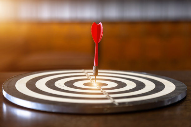 红色的飞镖箭击中靶心上的镖靶与太阳光复古风格，目标营销和商业成功的概念图片下载