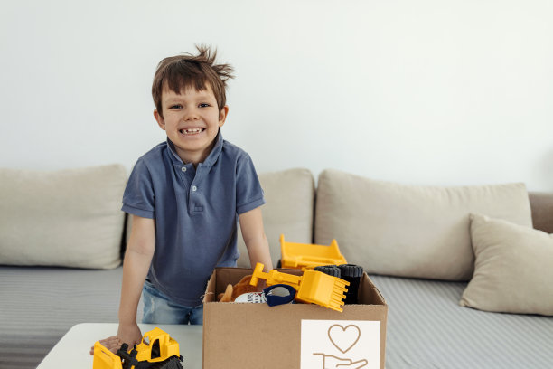 男孩把他的玩具装在纸板箱里捐赠。图片下载
