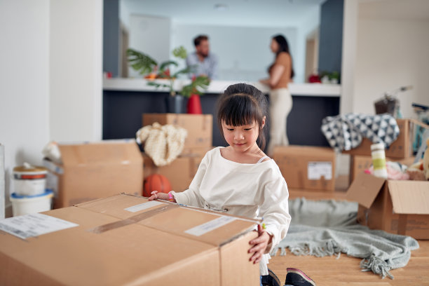 可爱的亚洲小女孩打开她的玩具和她的父母在背景。图片下载