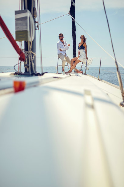 一对年轻夫妇坐在游艇的船头，享受着在海上航行的乐趣。夏天，大海，假期，感情图片下载