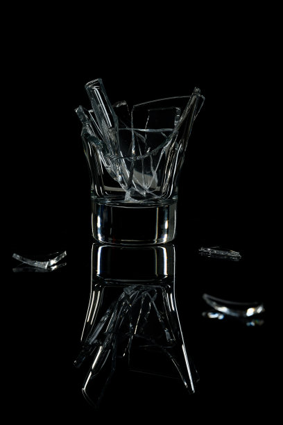 一个破碎的鸡尾酒杯放在一面黑色的镜子上。图片下载