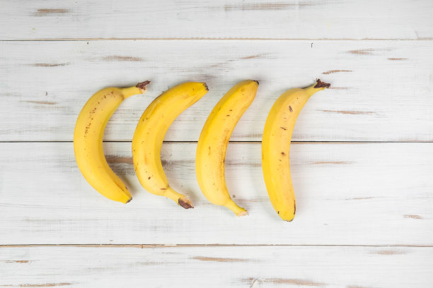 木制背景上的几根香蕉。普通的带斑点的香蕉。图片下载