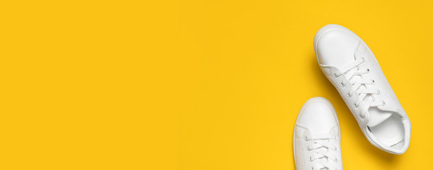 白色妇女的皮革运动鞋在黄色的背景顶视图平躺。时尚的青年运动鞋、运动鞋、真皮皮鞋。简约的鞋店广告时尚风格鞋的背景图片下载
