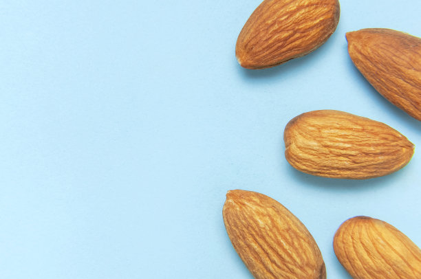 创新食品布局。杏仁在蓝色背景顶视图复制空间。食品概念，健康营养，坚果，健康脂肪。平的。杏仁的模式。有机健康的素食小吃微距镜头图片下载