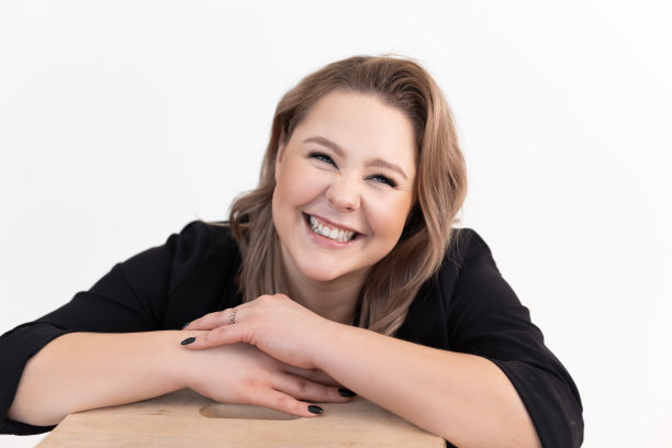 迷人的中年胖女人的肖像，长长的黑发和化妆穿着黑色的开襟羊毛衫，坐在桌子旁。图片下载