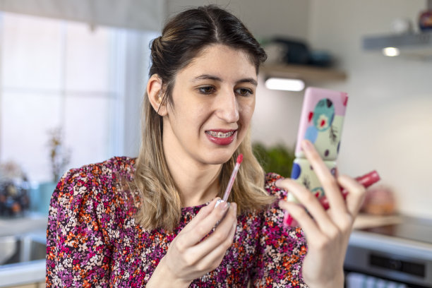 一个漂亮的年轻女人在涂口红。图片下载