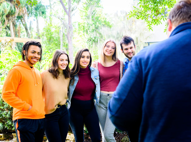 一名男子正在给一群快乐的多样化的朋友拍照，他们是大学生，z一代年轻人，在一起图片下载