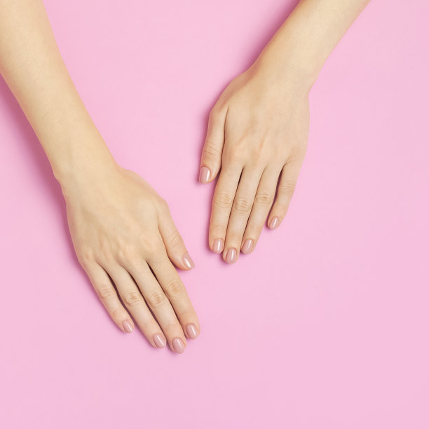 时尚漂亮温柔的美甲。年轻女子的手在粉红色的背景顶视图平躺复制空间。天然指甲，指甲油，自我护理，美容时尚。美甲、美容院广告图片下载