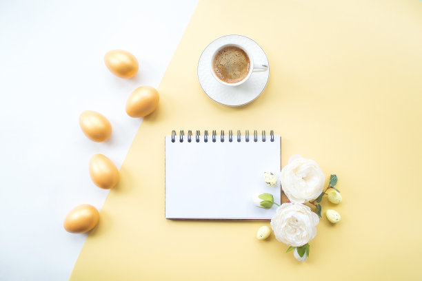 金色的复活节彩蛋，咖啡杯，精致的花和笔记本与地方的文本在黄色的背景上。时髦的公寓。最小的概念。图片下载