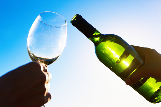 背光映照着天空，白葡萄酒即将倒进酒杯图片下载