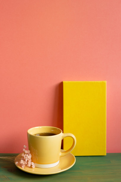 黄色的笔记本和咖啡在绿色的木桌上。粉红色的背景墙。本空间图片下载