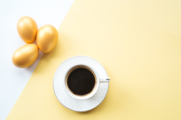 金色的复活节彩蛋和咖啡杯与地方的文本在黄色的背景上。时髦的公寓。最小的概念复活节。图片下载