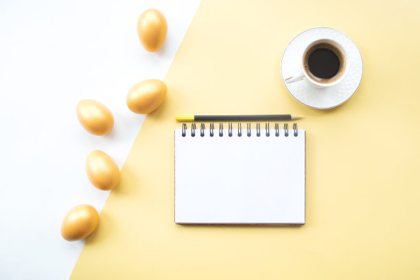 金色的复活节彩蛋，咖啡杯和笔记本与地方的文本在黄色的背景上。时髦的公寓。最小的概念。图片下载
