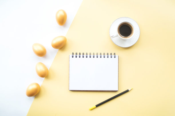 金色的复活节彩蛋，咖啡杯和笔记本与地方的文本在黄色的背景上。时髦的公寓。最小的概念。图片下载