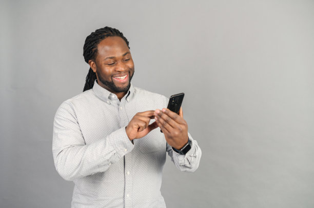 面带微笑的非裔美国人和一个被灰色孤立的智能手机男人图片下载