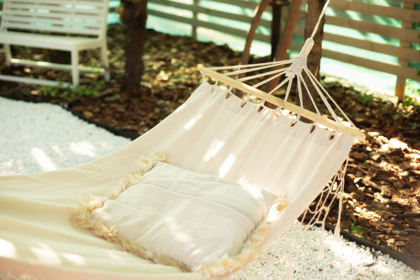 舒适的吊床和枕头挂在树上。户外娱乐的概念。波西米亚风格的吊床。白色的吊床和枕头，在一个夏天的下午，在后院花园的树荫下放松。图片下载