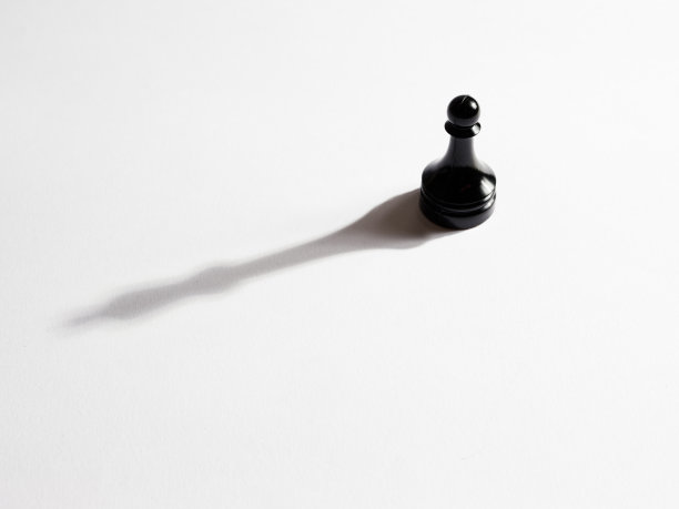 俯视一个黑色的国际象棋卒与一个国王的影子图片下载