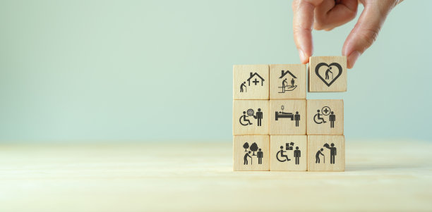 老年保健的概念。手握木制方块，上面有与老年护理、医疗、康复服务、护理有关的图标，以提高老年生活质量。用于横幅，背景图片下载