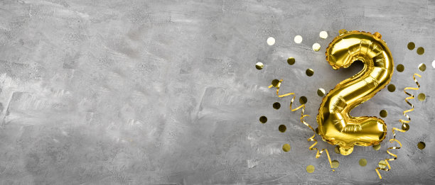 黄色铝箔气球号码，二号号码在混凝土背景上。有字母的生日卡片。周年的概念。周年纪念，生日，新年庆祝。图片下载