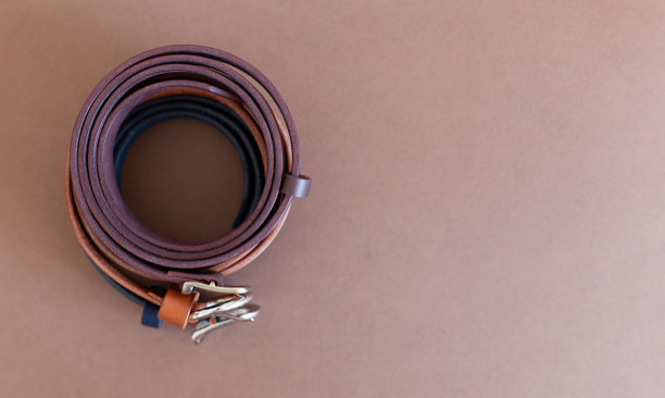 棕色的背景上放着几根手工制作的真皮女士腰带。平面与文本空间图片下载