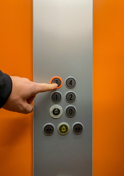 男人的手按下了电梯的按钮上了三楼。图片下载