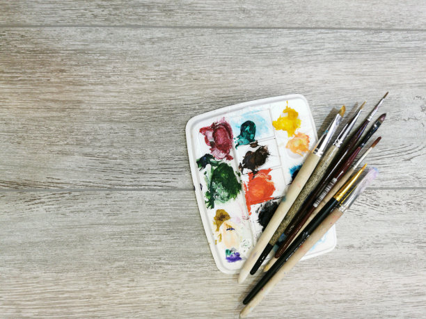 多色笔触，绘画后笔刷和调色板上的颜料残留。接近纹理木质背景。文本的空闲空间。图片下载