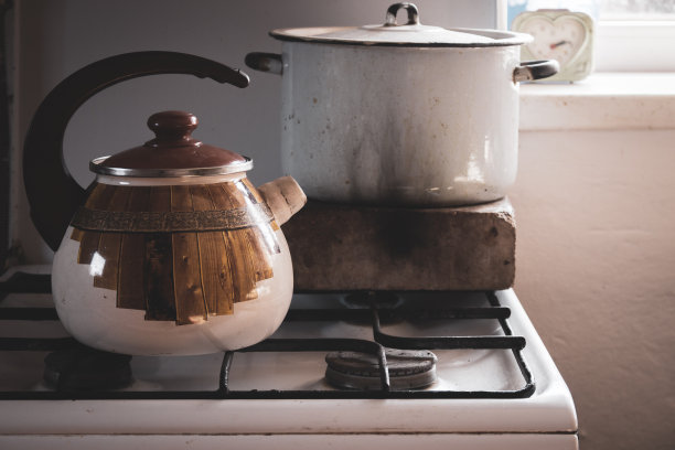 煤气炉上的老式水壶和汤锅。村庄里的复古厨具。乡村家庭设备。烤箱上的旧茶壶和煮锅。烹饪概念。图片下载