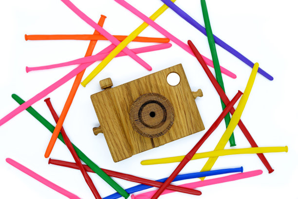 白色背景上的木制相机，周围有彩色条纹球图片下载