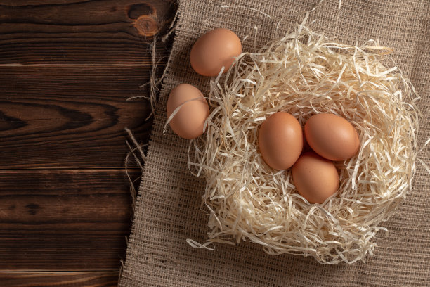 干草和鸡蛋在木制背景上。图片下载