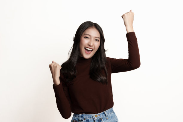 工作室肖像照片的年轻亚洲妇女感到高兴或兴奋，举手表示享受的情绪，面部表情。图片下载