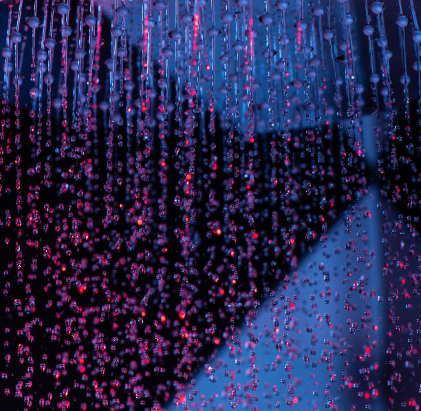 淋浴时，水珠从洒水罐里滴下来，发出红蓝的光。水滴特写。流动的水。浴室里有一个大的圆形喷壶。“n图片下载