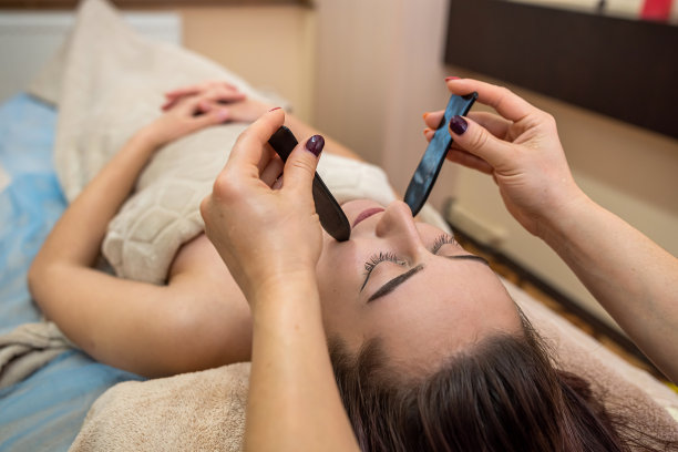 一个女孩在美容院做一个很棒的面部按摩，用石头增加淋巴流动。图片下载