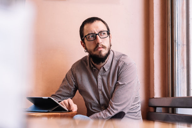 一个年轻的商人在咖啡馆里用他的平板电脑工作图片下载