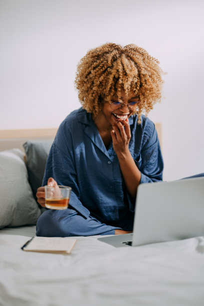 快乐的女商人在床上使用笔记本电脑图片下载