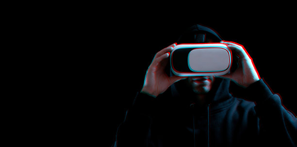 Vr护目镜使虚拟现实变得模糊。年轻人戴着数字头盔，在黑暗的背景下玩3d虚拟现实游戏。研究和虚拟世界的三维仿真与故障效应。图片下载