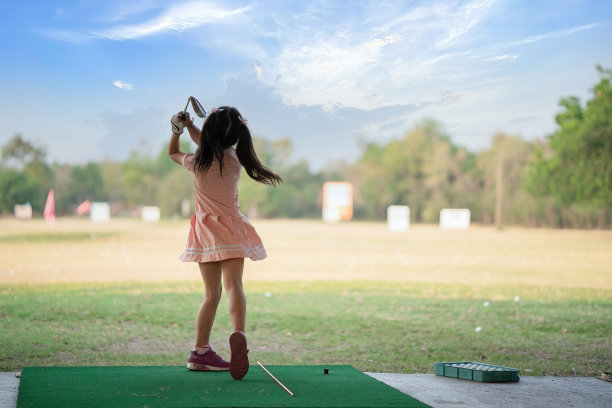 小女孩在高尔夫练习场练习高尔夫挥杆，从后面看图片下载