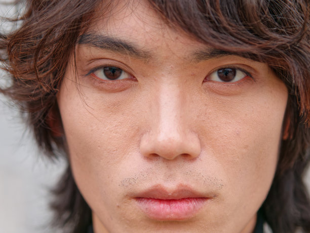 英俊的中国年轻男子的肖像在黑色看着灰色墙壁背景的相机，自信的年轻男子的正面视图，近距离视图的头部拍摄。图片下载