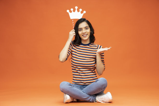 年轻女子坐在地板上，橙色背景的笔记本电脑，库存照片图片下载