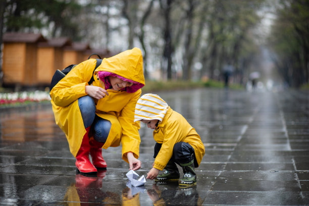 孩子和他的妈妈在水坑里玩纸船图片下载