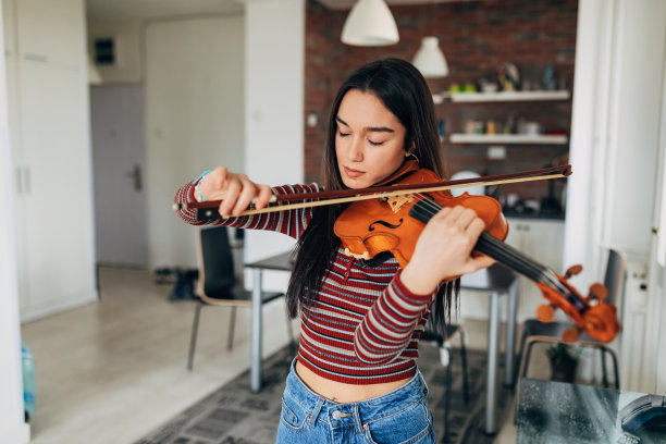 这位年轻的小提琴家正在家里完善她的小提琴演奏技巧。图片下载