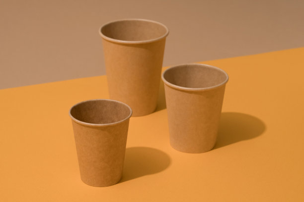 牛皮纸生态咖啡杯在橙色和棕色的背景与复印空间。可持续食品包装概念，模型图片下载