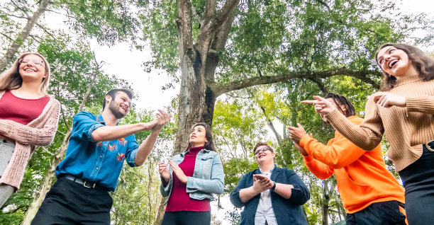 各种各样快乐的年轻人在户外欢笑、鼓掌、唱歌，青年团或俱乐部或团队建设图片下载